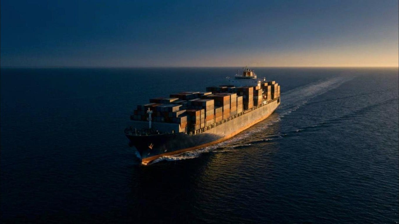 Container ship under way on open sea at dawn